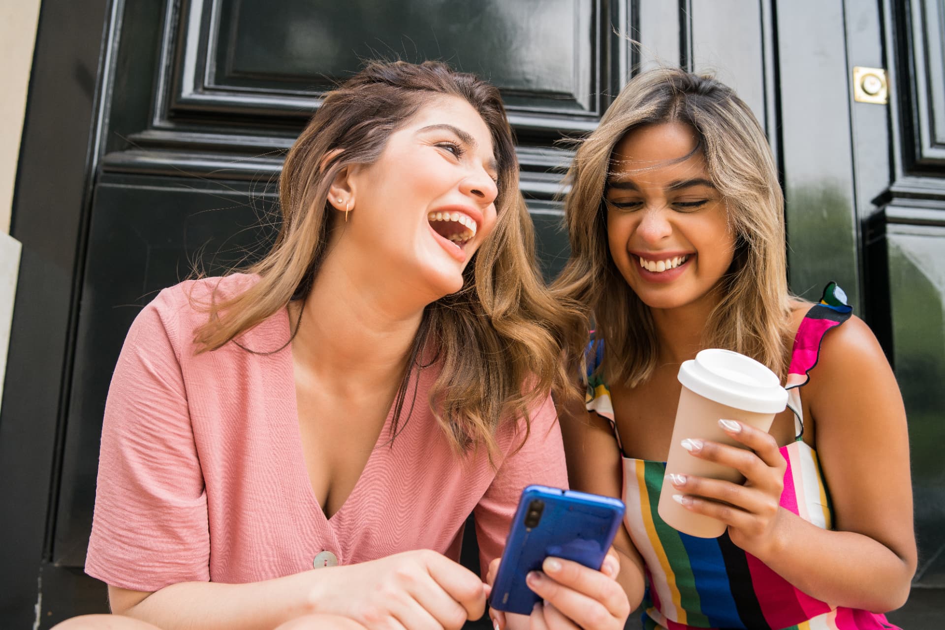 Two teenagers laughing on a suburban front porch at dusk