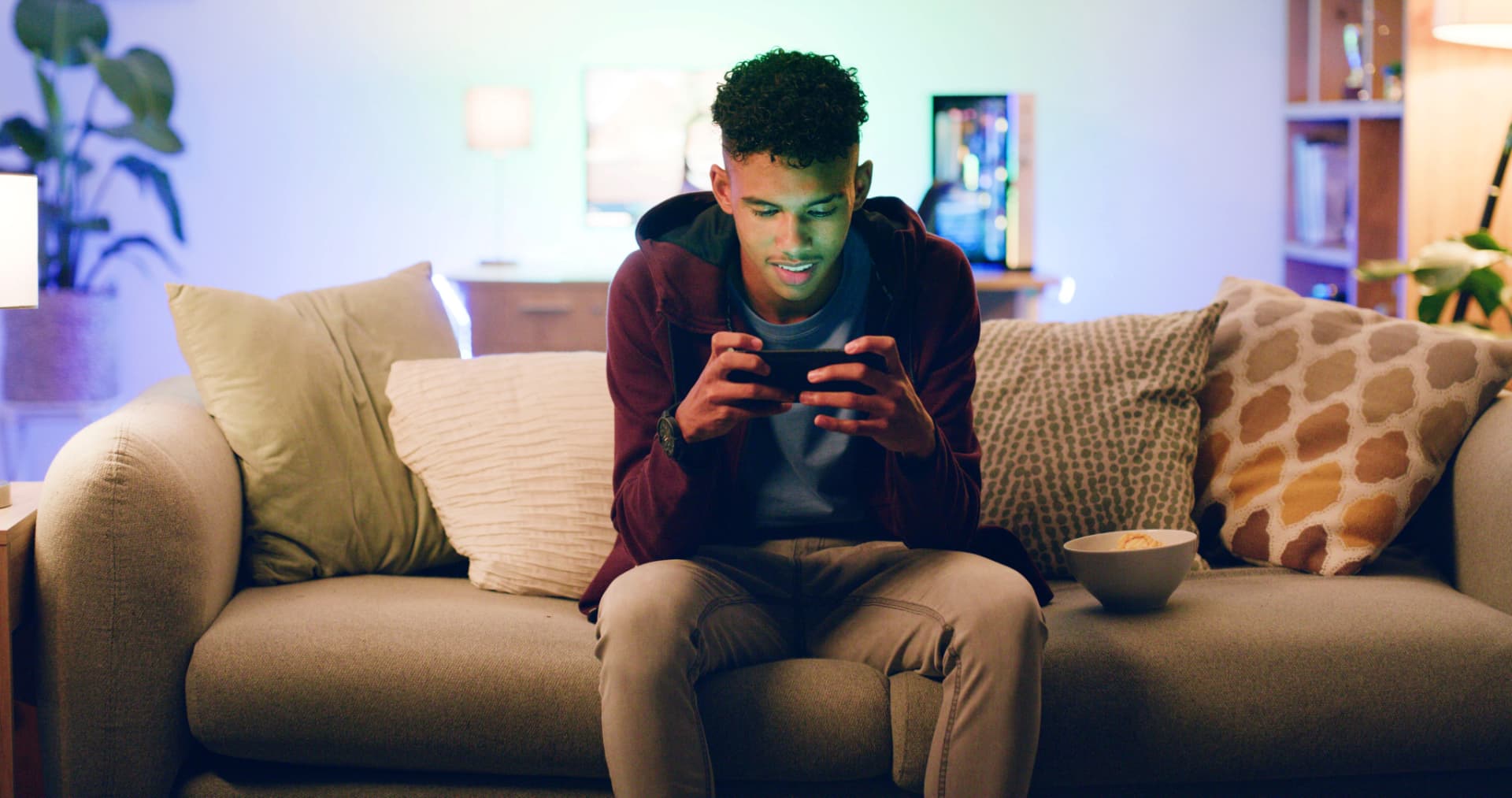 Young man playing a game on his phone at home in the evening