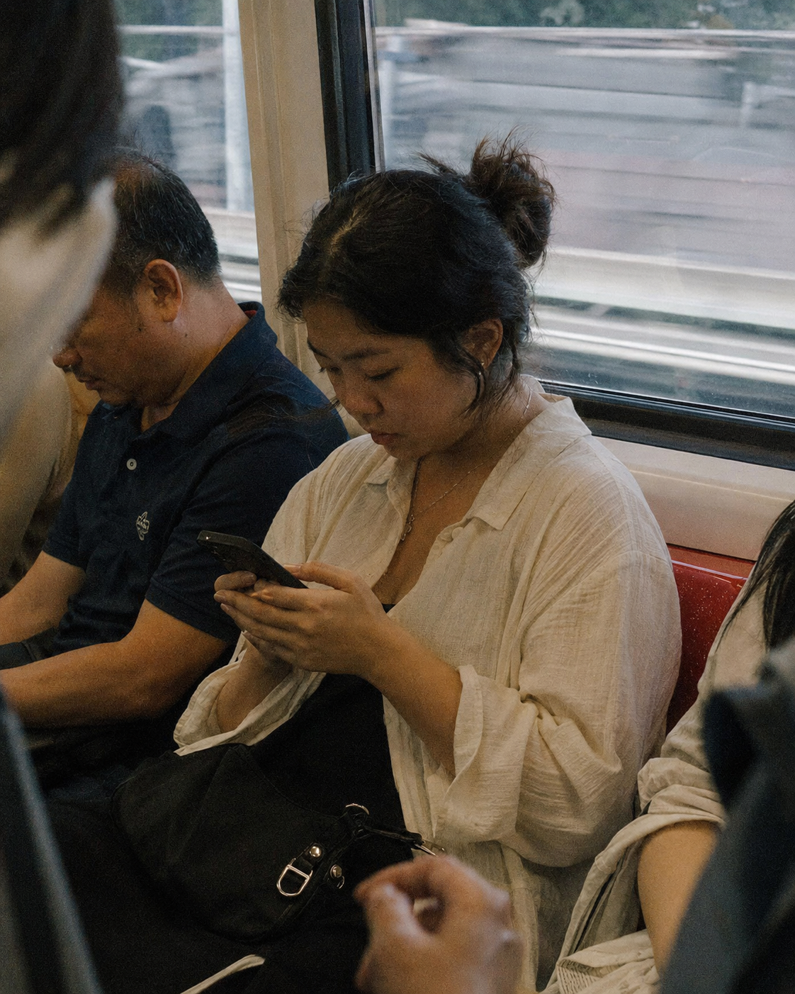 Woman using her phone on a train, evening light through the window